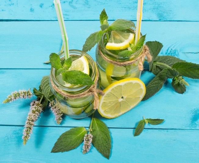 Water with fresh lemon, green leaves mint and cucumber