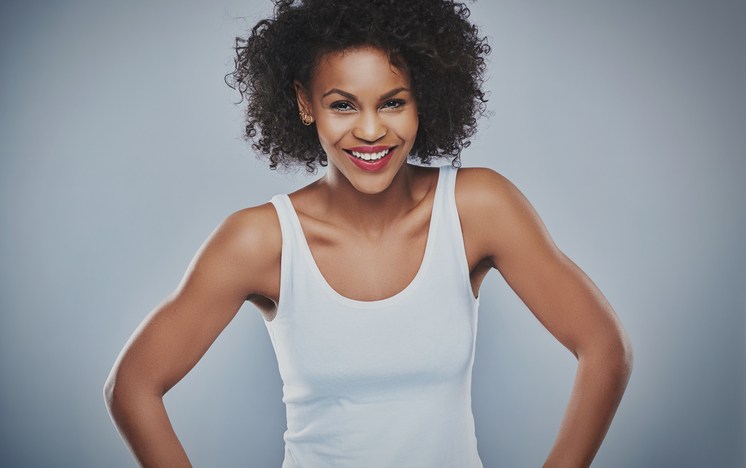 Single beautiful carefree and happy woman posing over gray background with copy space to side