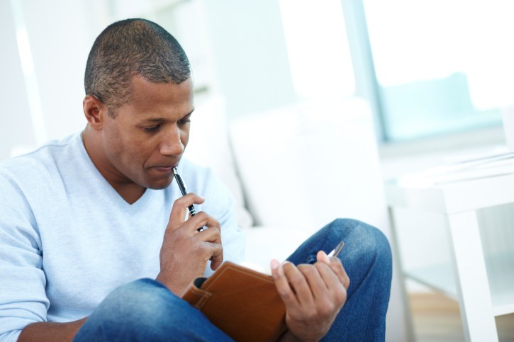 man writing in journal