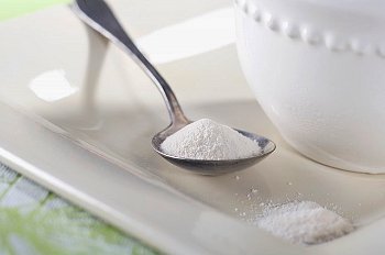 A spoonful of artificial sweetener sitting on a white ceramic tray