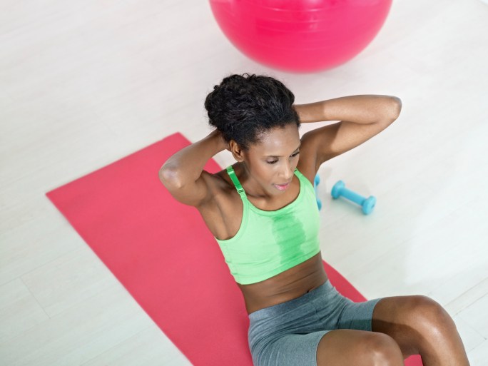 african woman doing series of crunch in gym