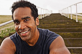 A smiling man sitting on stairs looking sweaty