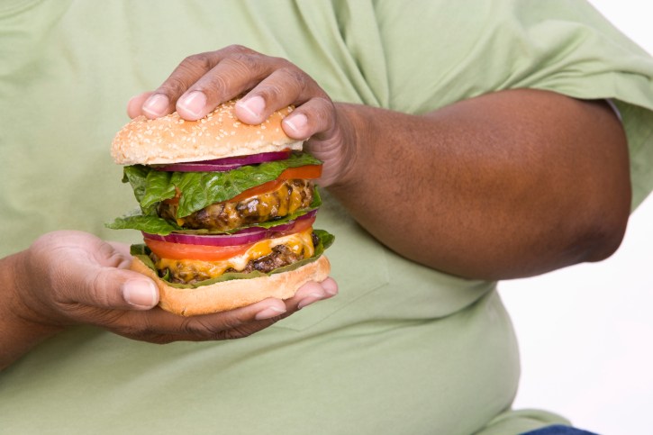 obese man holding double cheeseburger
