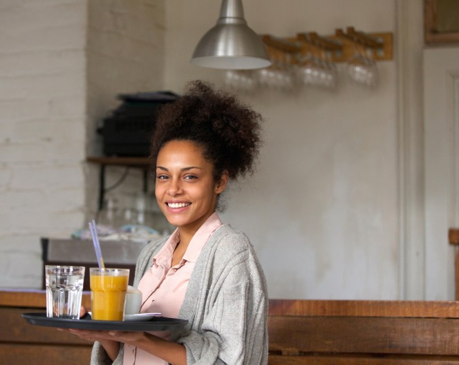Smiling waitress holding tray of drinks in restaurant