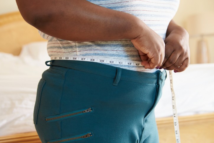 overweight person with a tape measure around waist