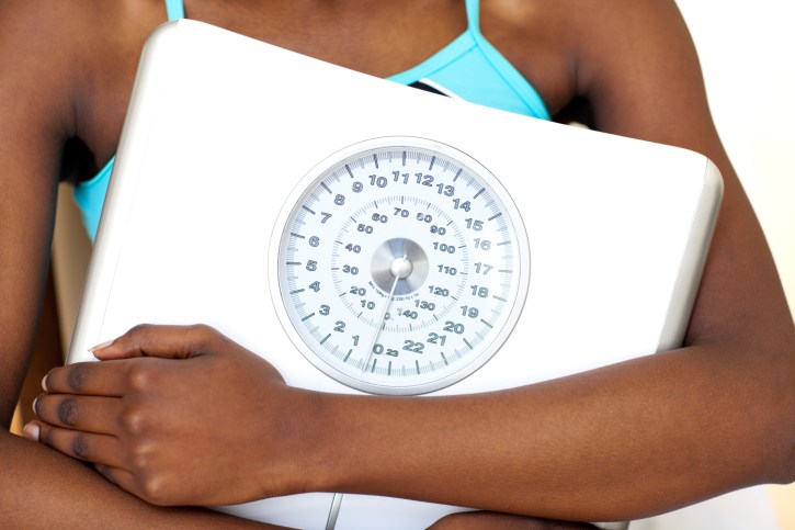 woman wearing gym clothes holding scale