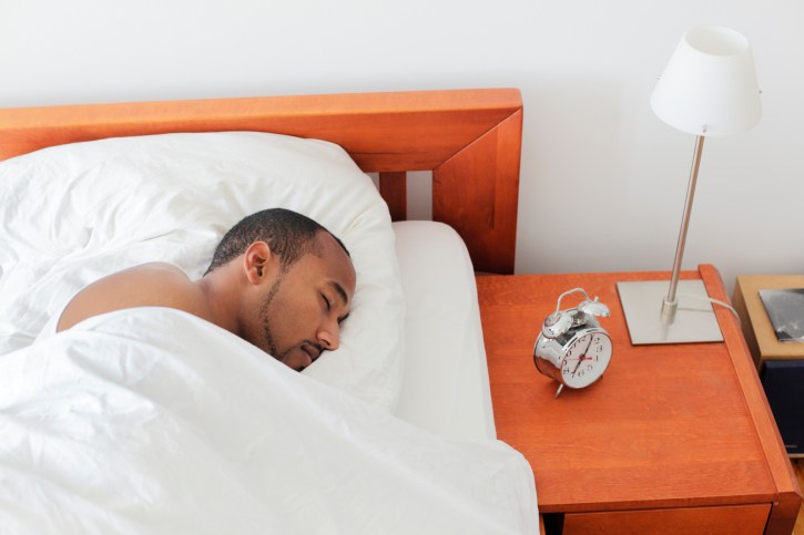 Young man sleeping next to Alarm Clock