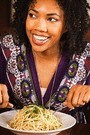 african american woman eating pasta