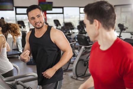 Friends doing cardio and talking at gym