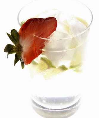 Mineral water with lime wedges, ice cubes and strawberry